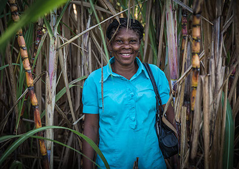 Saincia, woman in Haiti, standing outside, smiling.